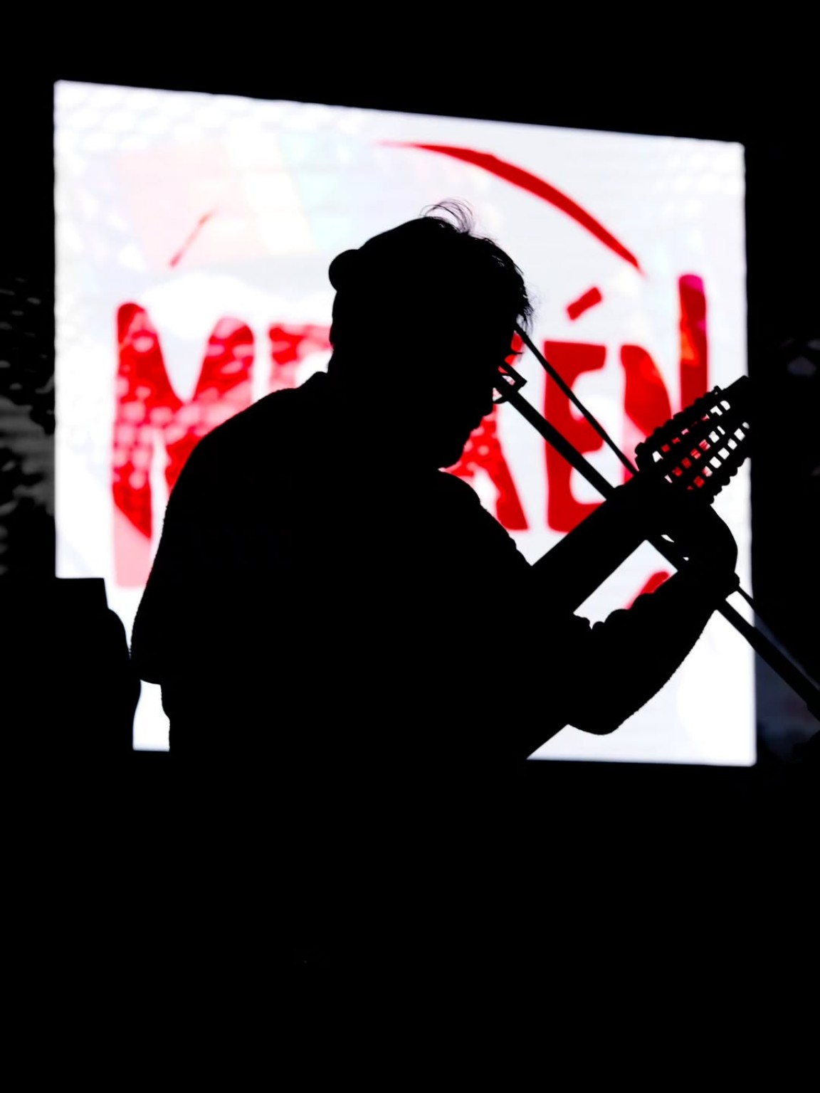 Silueta de un músico de cuerdas frente al escenario iluminado